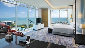 A hotel room with a large window, a bed, a desk with a computer, and a seating area with a view of the sea. - Intercontinental Xiamen by IHG (Xiamen)