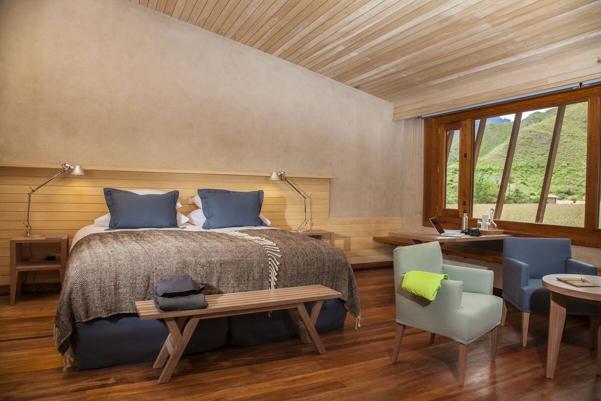 A modern bedroom with a large bed, bedside tables, a desk, and a chair.