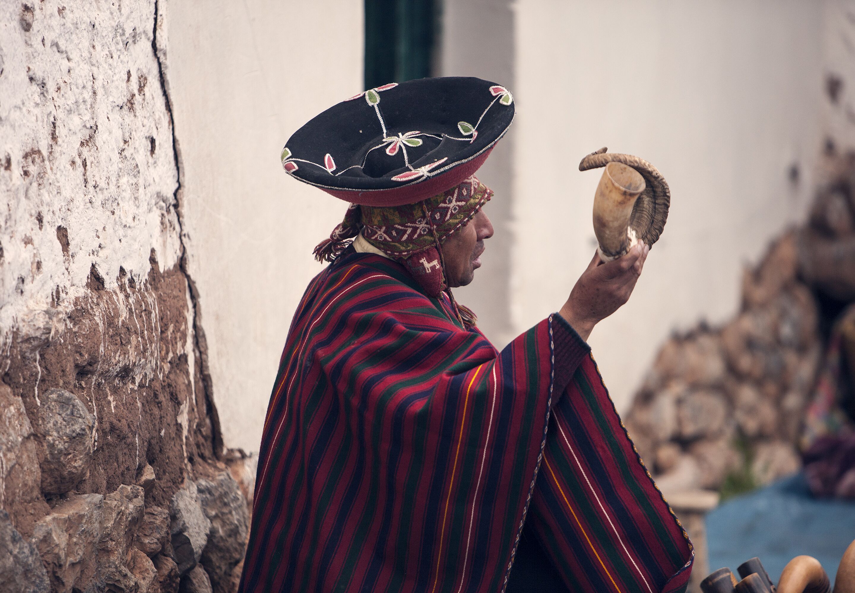 Une personne vêtue d’un costume traditionnel tenant un objet en forme de corne.