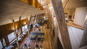 A spacious restaurant with high ceilings and wooden beams, featuring multiple dining areas and a central seating area. - Explora Valle Sagrado (Huayllabamba)