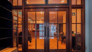 A hotel entrance with a wooden door, a bench outside, and a visible interior with a shoe display. - Double Black Hotel (Hakuba)