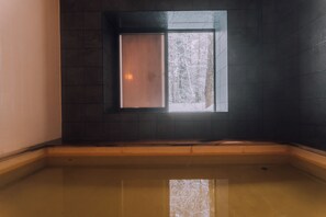 A corner room with a small window, a wooden bench, and a tiled floor. - Double Black Hotel (Hakuba)