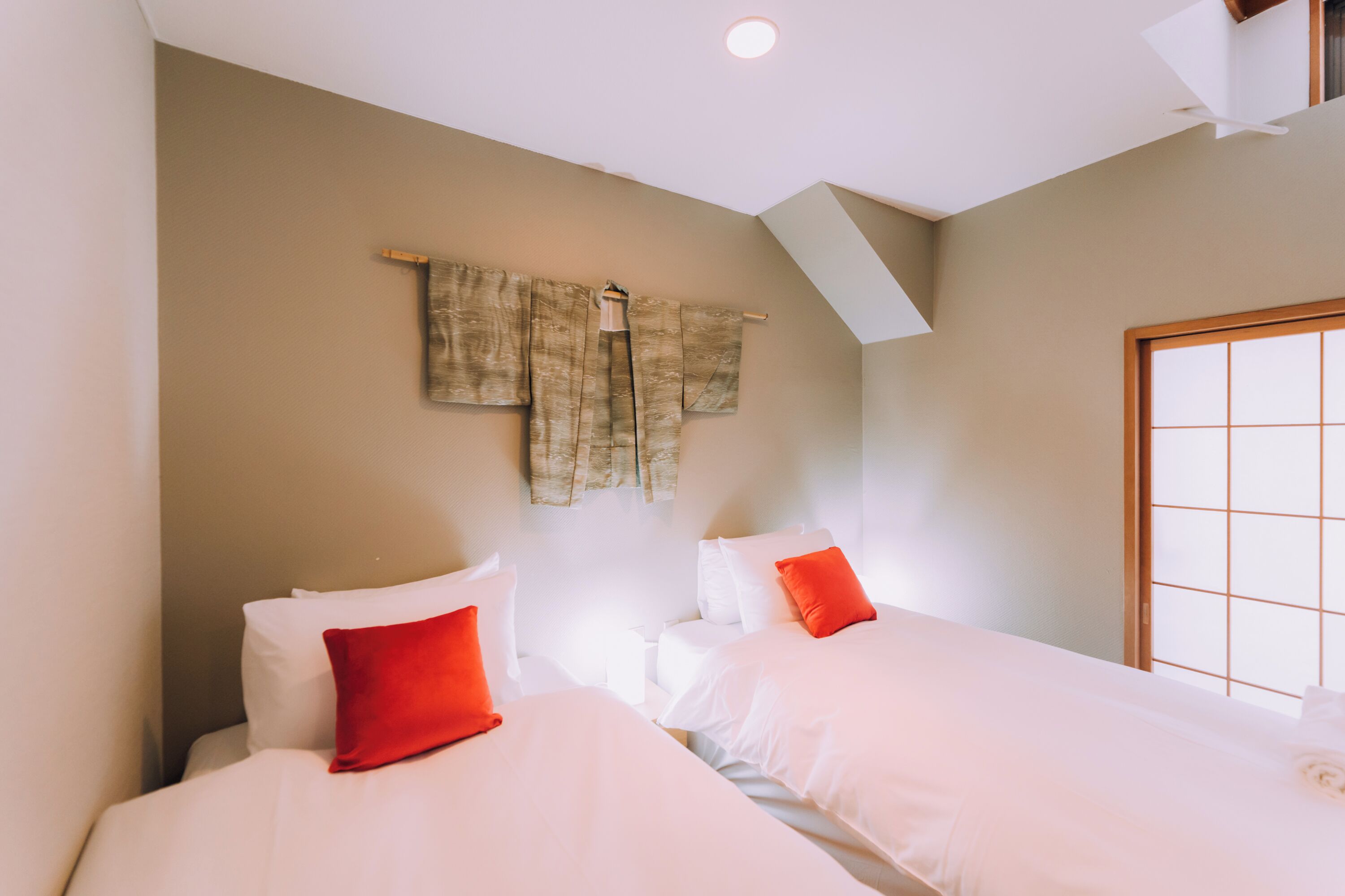 A hotel room with two beds, a skylight, and a large window.