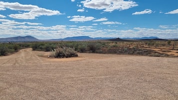 Un paisaje seco y abierto con vegetación escasa y montañas lejanas bajo un cielo parcialmente nublado.