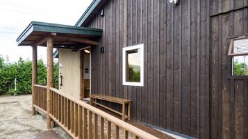 A wooden building with a porch, a bench, and a small window.