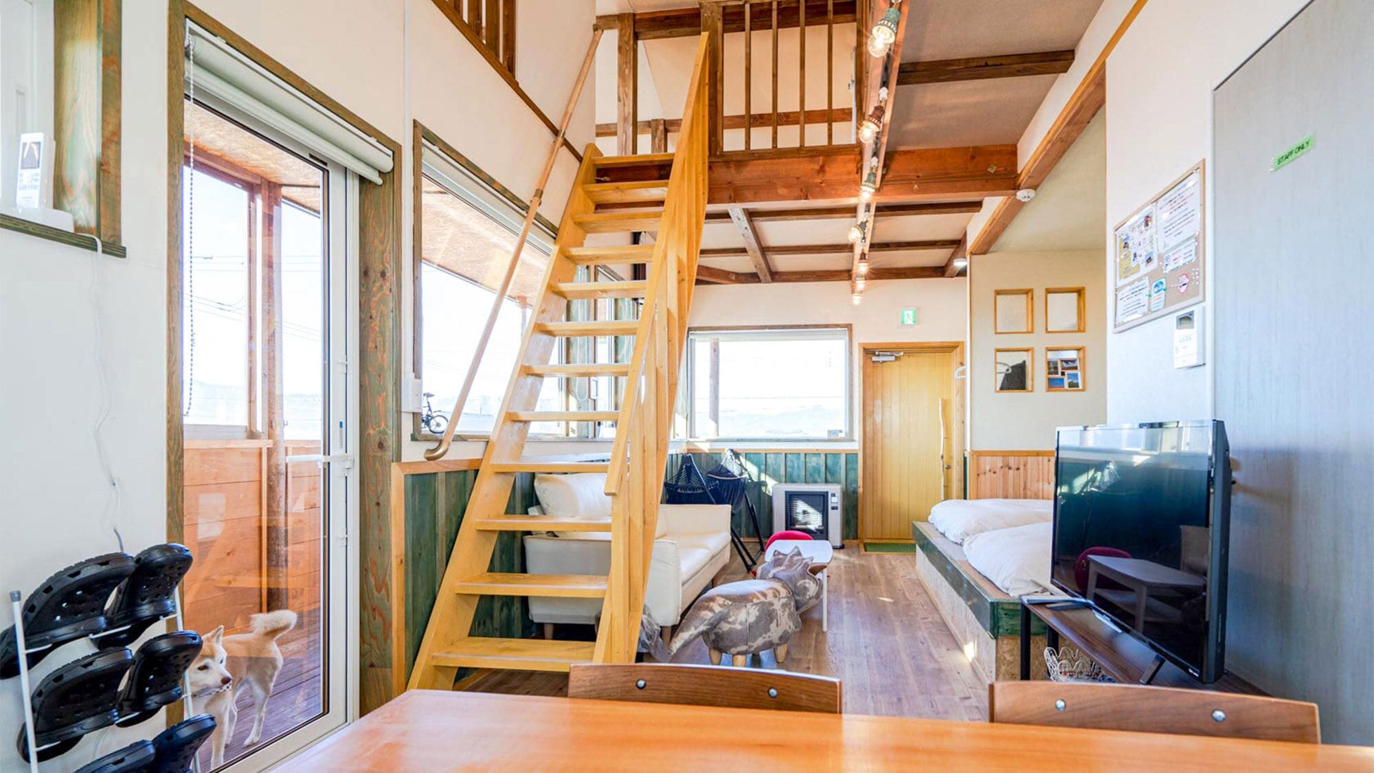 A compact room with a wooden ladder, a bed, a television, and a small table.