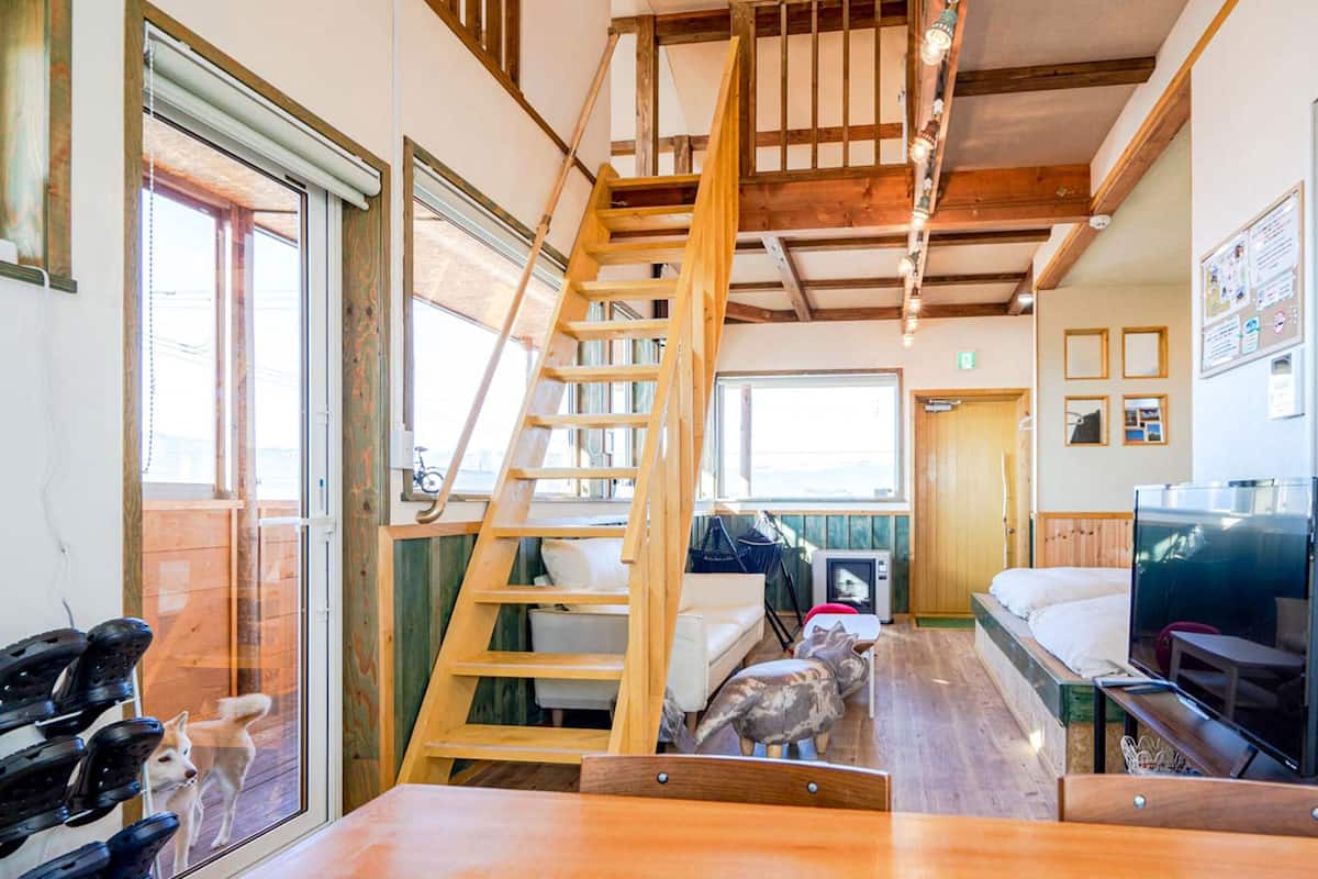 Une petite pièce comprenant une échelle en bois, un lit, une télévision et une petite table.