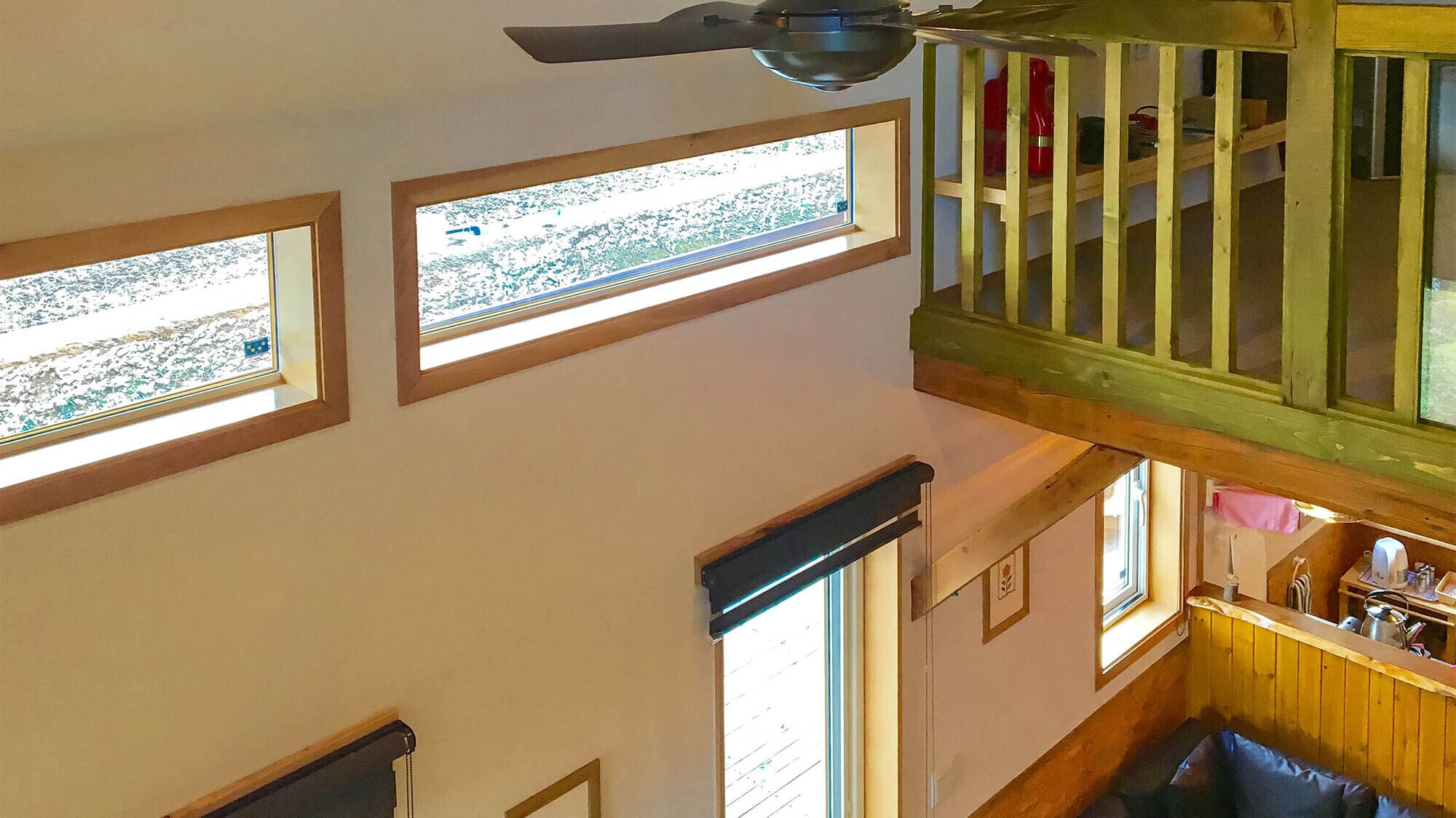 A high-ceilinged room with skylights, a wooden staircase, and a view of the outdoors.