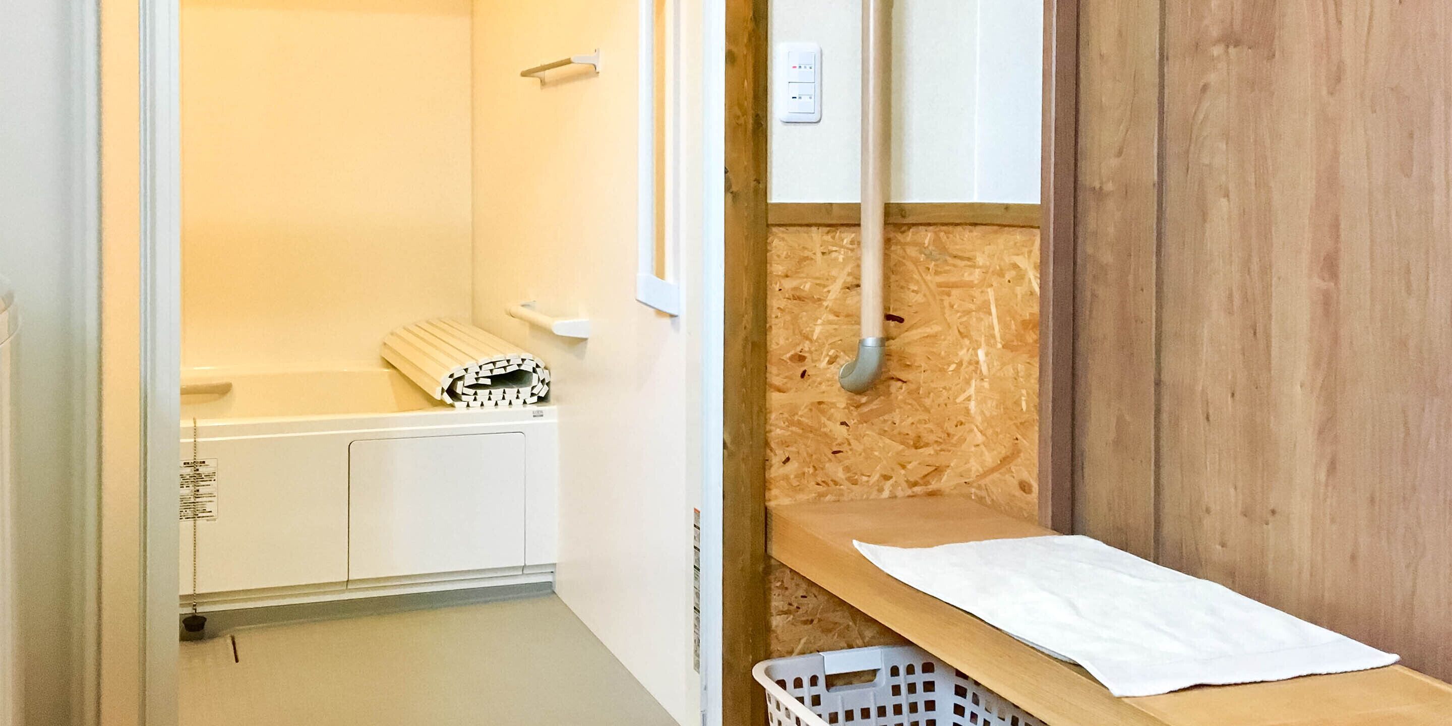 Une salle de bain avec un plancher en bois, une baignoire blanche, un porte-serviettes et une étagère en bois.