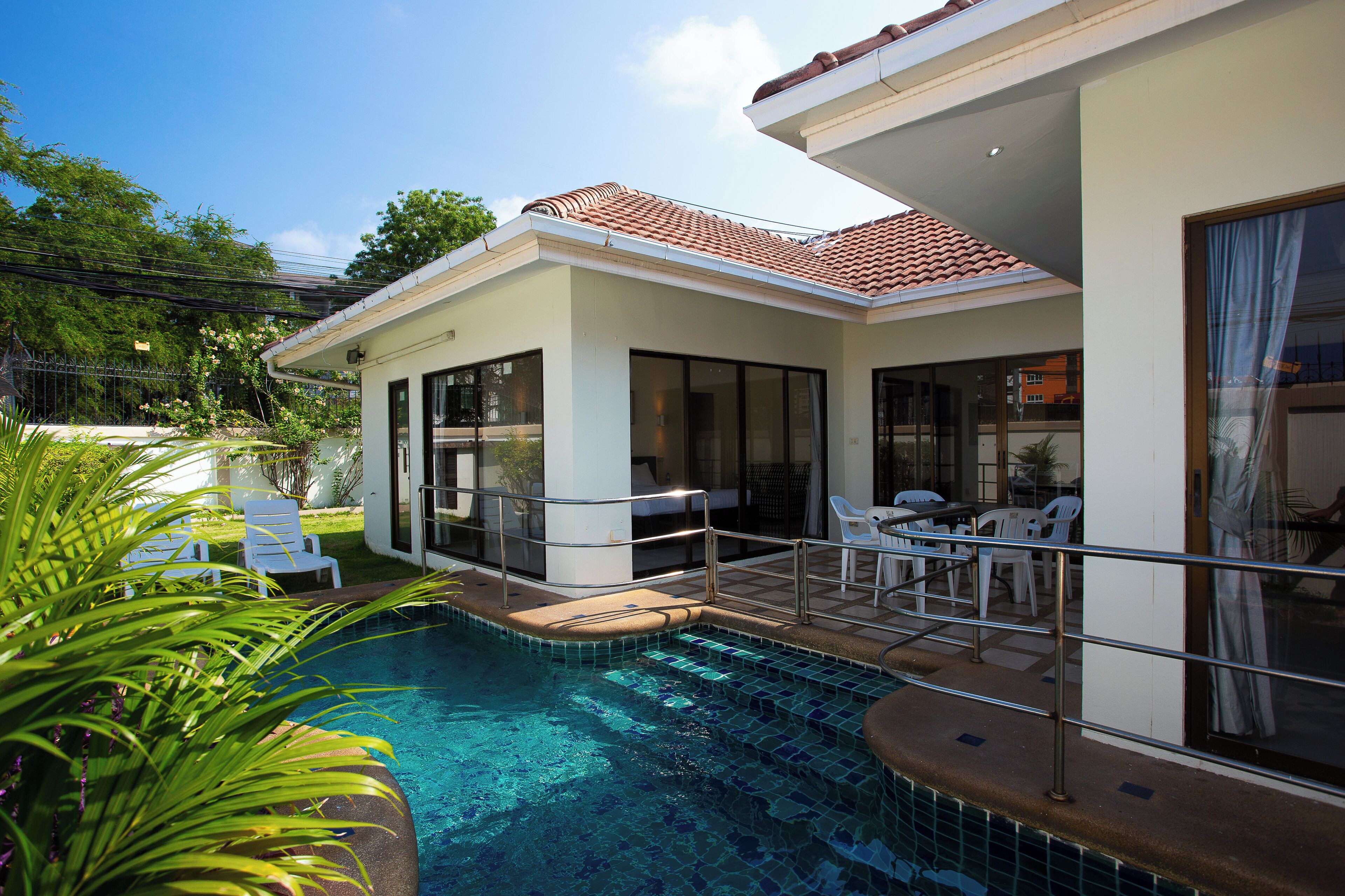 Una casa moderna con piscina, ventanas amplias y mobiliario exterior.