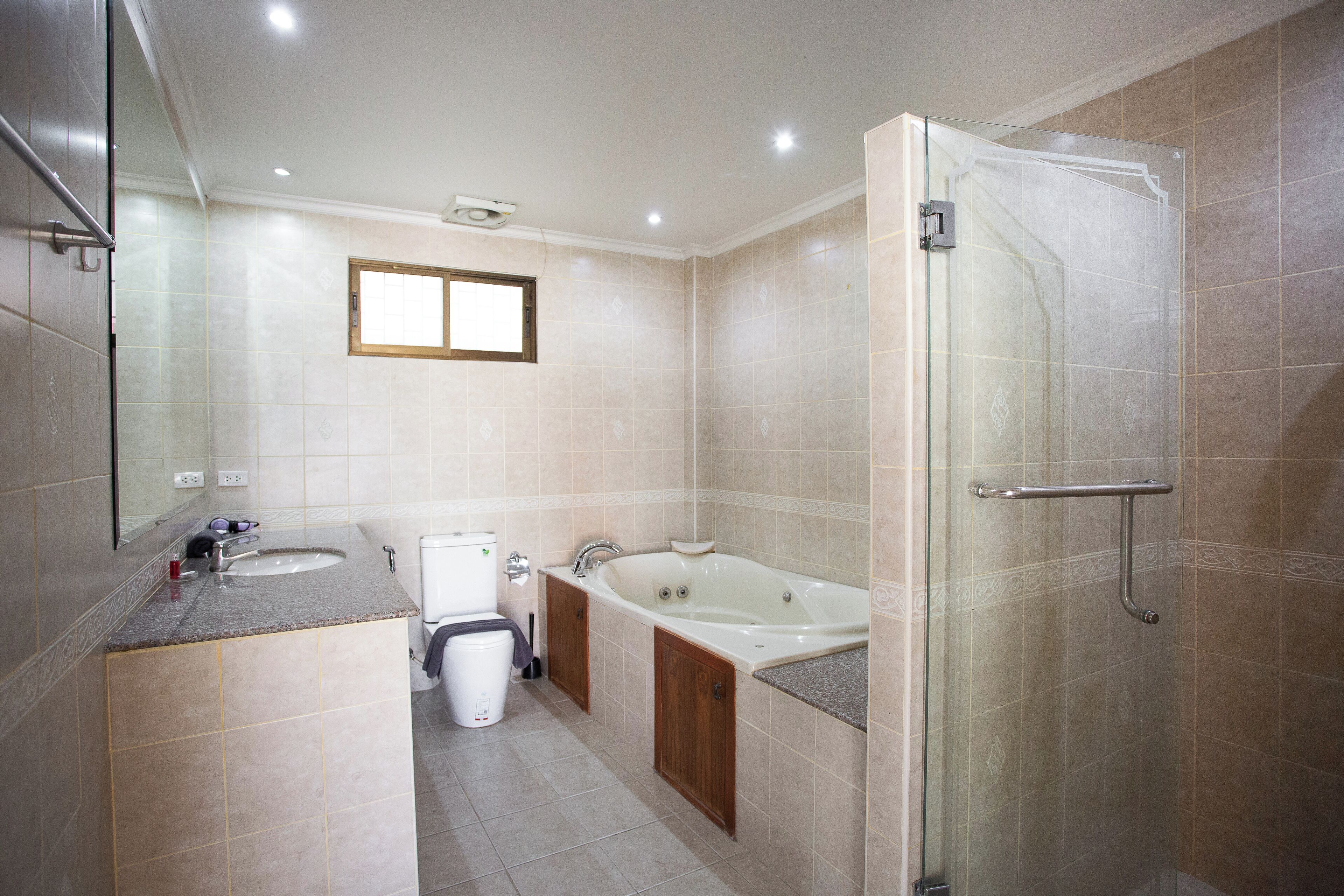 Un baño moderno con ducha de vidrio, bañera independiente y lavabo con tocador.