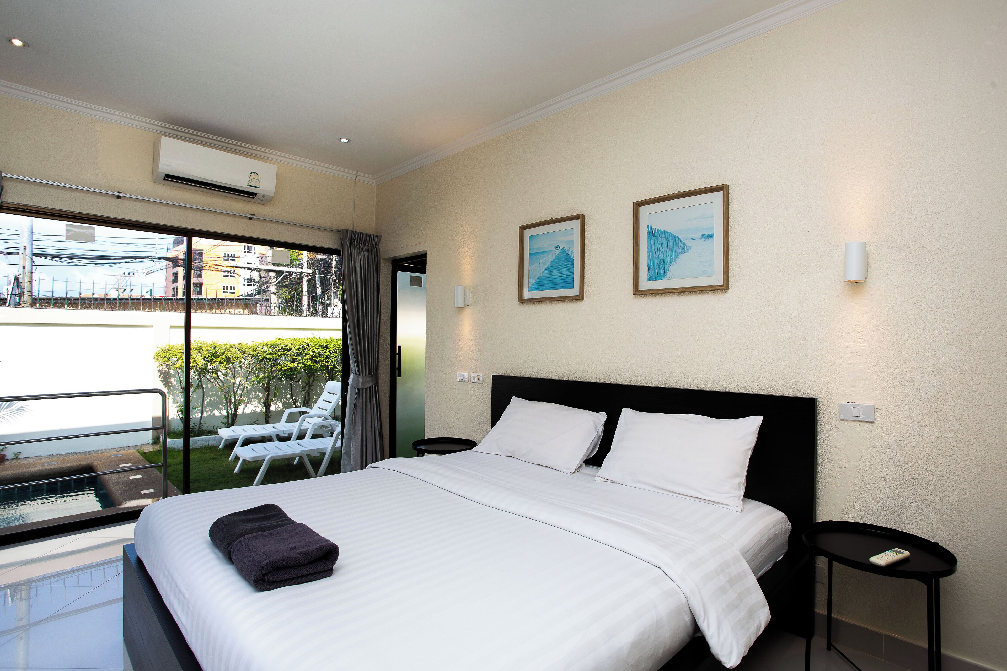 A hotel room with a large bed, a small table, a chair, and a view of the outdoors.