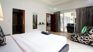 A hotel room with a large bed, a sofa, a mirror, and a sliding glass door leading to a balcony.