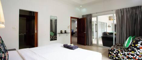 Une chambre d’hôtel avec un grand lit, un canapé, un miroir et une porte-fenêtre coulissante donnant sur un balcon.