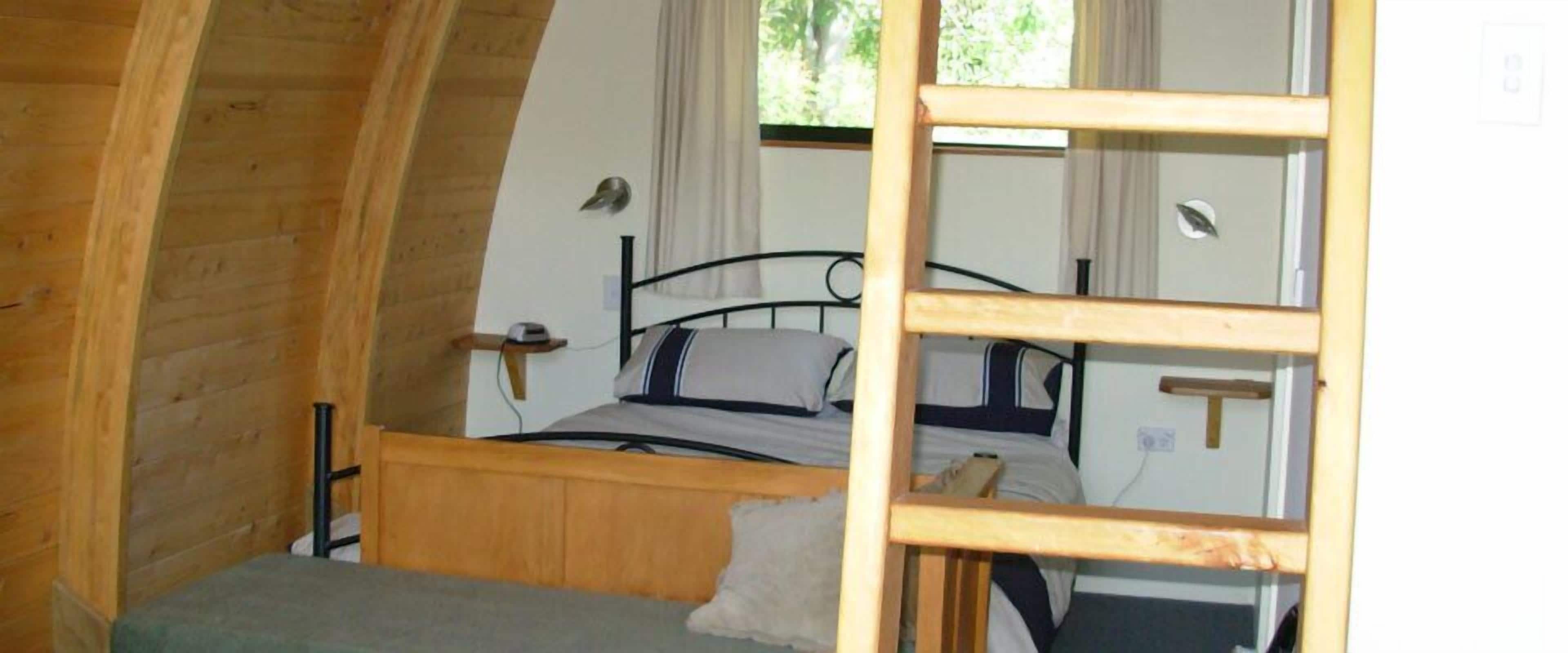 Una habitación pequeña con una cama individual, paredes de madera y techo inclinado.