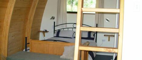 Una habitación pequeña con una cama individual, paredes de madera y techo inclinado.