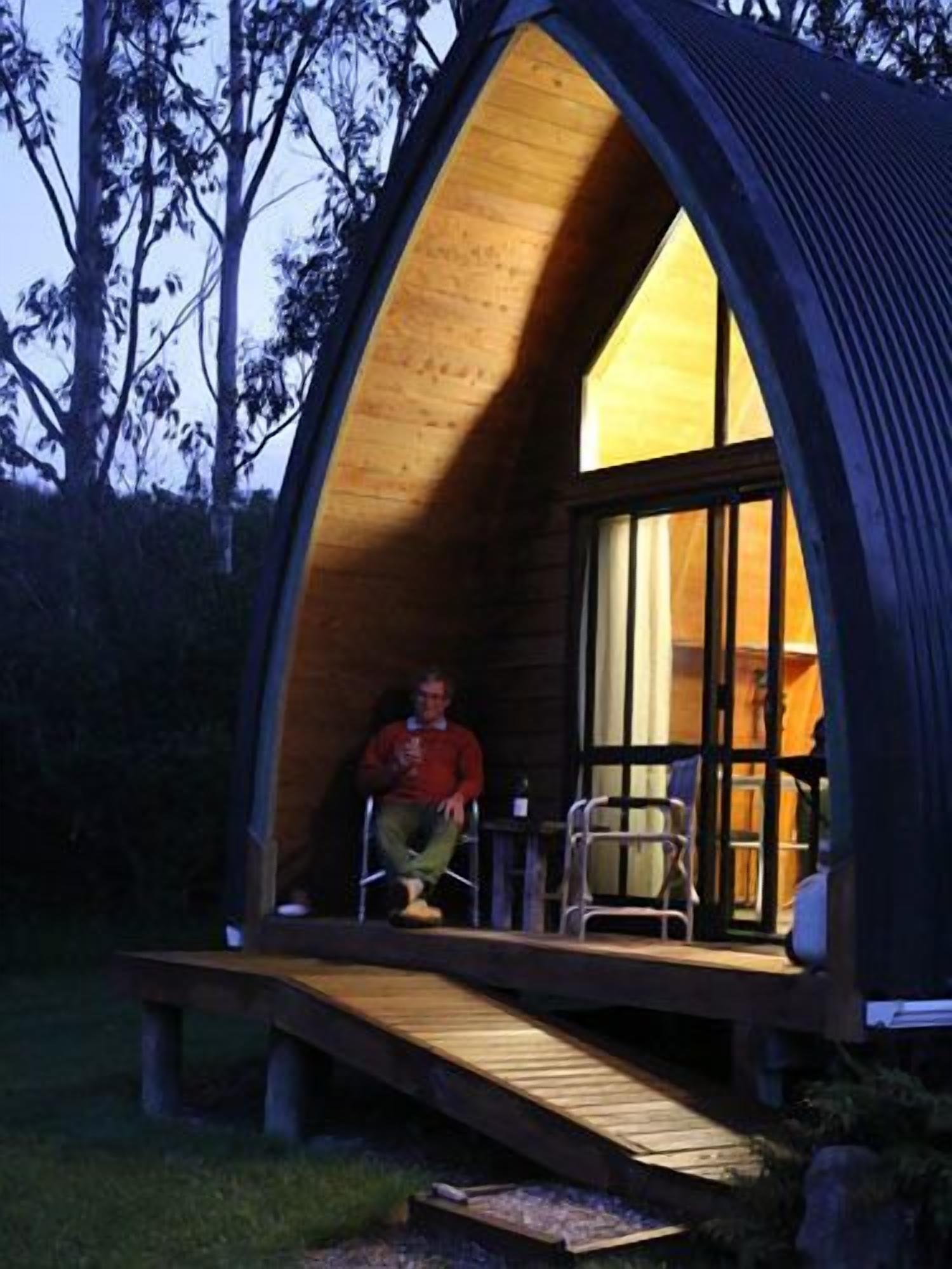 A cozy, semi-open wooden structure with a ramp leading to a porch area.