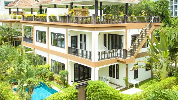 A multi-story hotel with balconies, a swimming pool, and lush greenery. - Sweet Villa Pattaya (Pattaya)