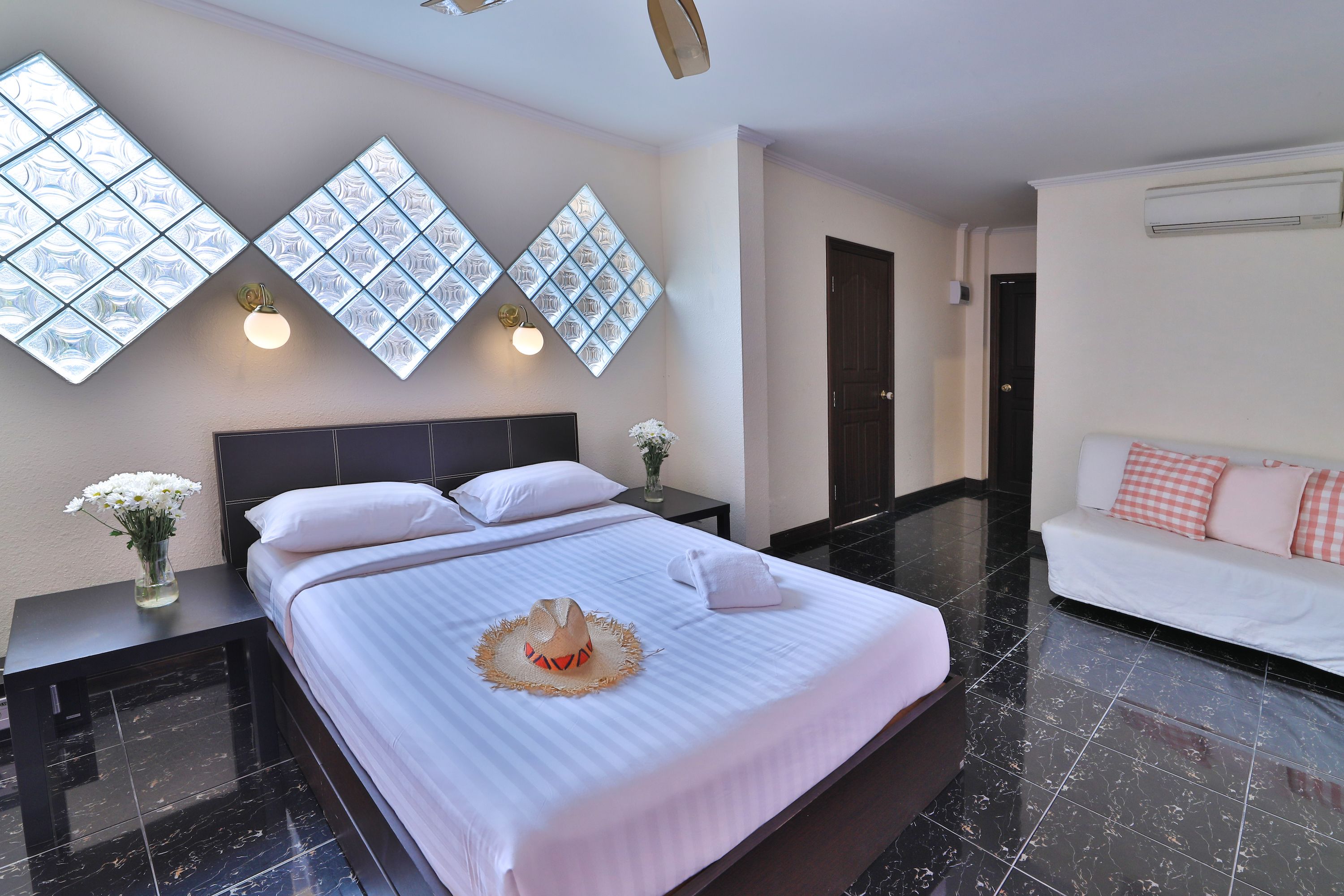 Habitación de hotel con una cama grande, dos mesitas de noche, un sofá y paneles decorativos en la pared.