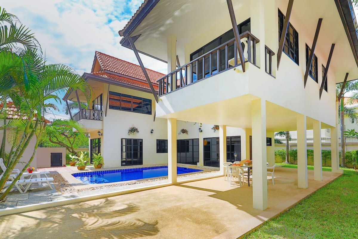 A two-story house with a swimming pool, outdoor seating area, and a covered patio.