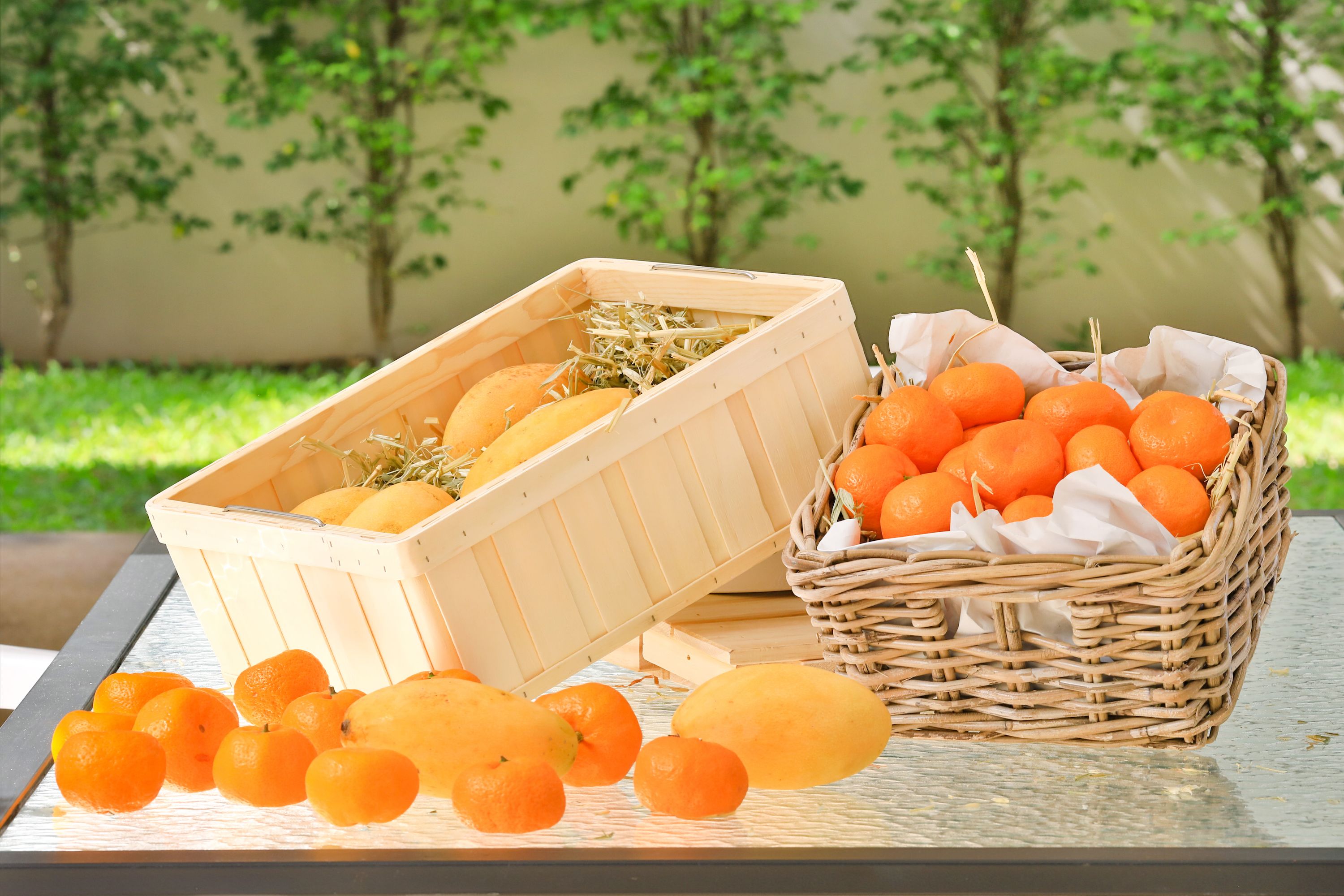 A table with a wooden crate and a wicker basket containing oranges and lemons.