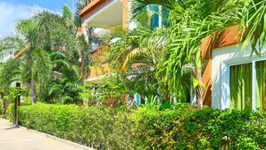 A hotel with a balcony, lush greenery, and a clear blue sky. - Sweet Villa Pattaya (Pattaya)