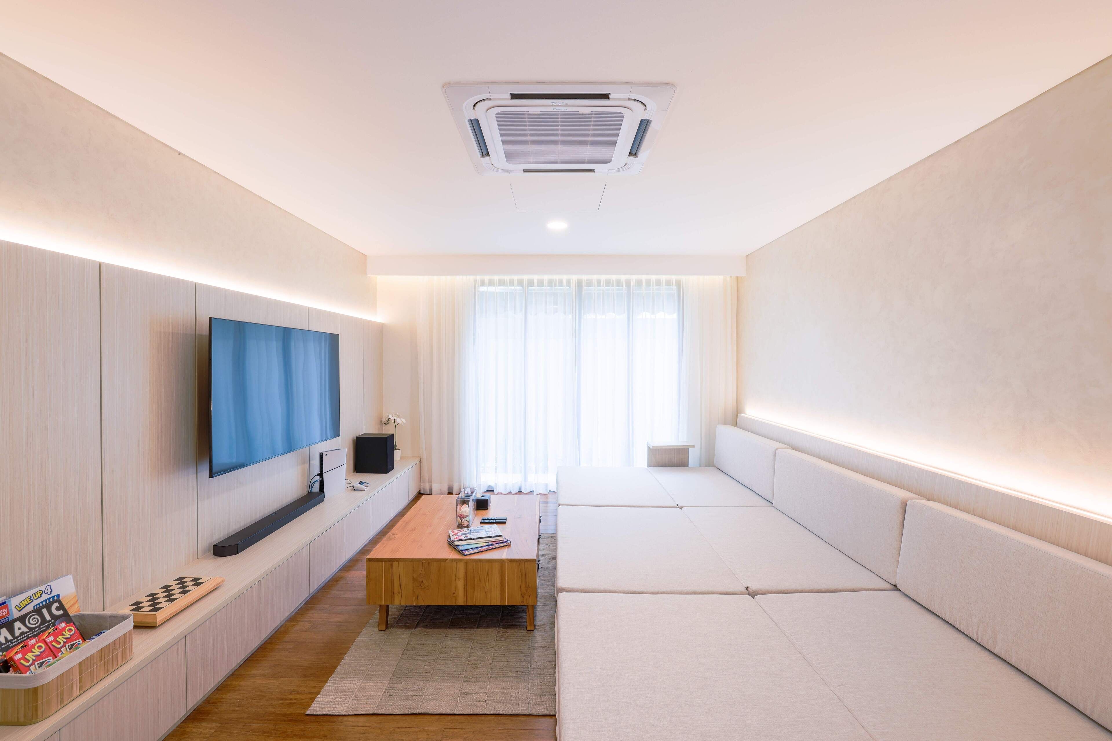 Una sala de estar moderna con un televisor de pantalla plana, una mesa de centro de madera y un sofá.