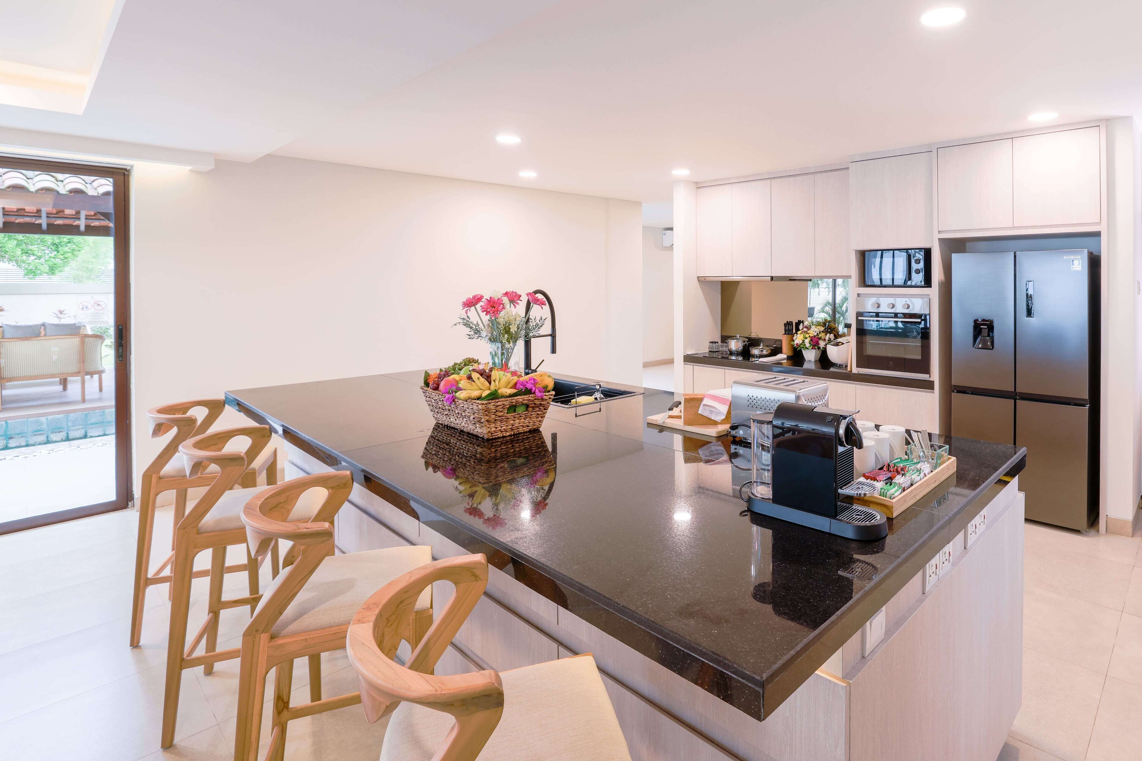 A modern kitchen with a central island, bar stools, and stainless steel appliances.