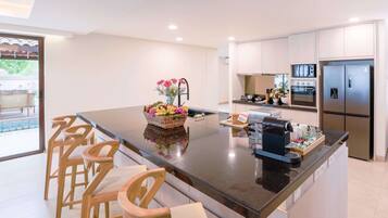 A modern kitchen with a central island, bar stools, and stainless steel appliances.