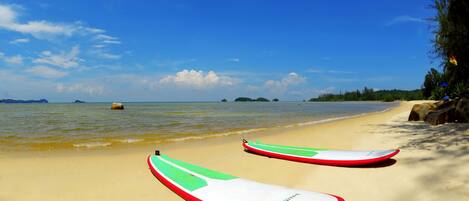 A beach with two surfboards and a clear blue sky.