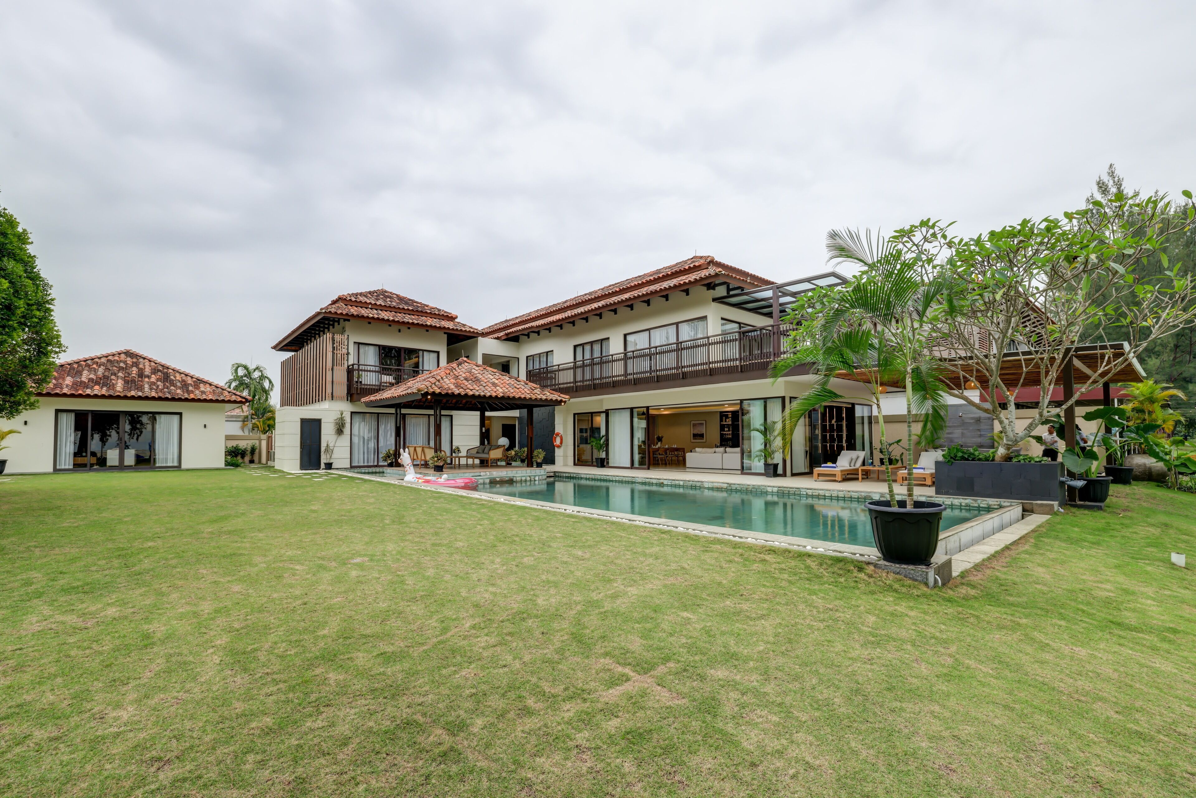 A residential property with a swimming pool, multiple balconies, and a well-maintained lawn.