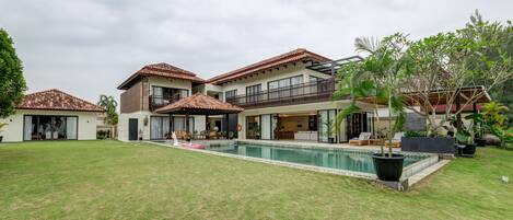A residential property with a swimming pool, multiple balconies, and a well-maintained lawn.