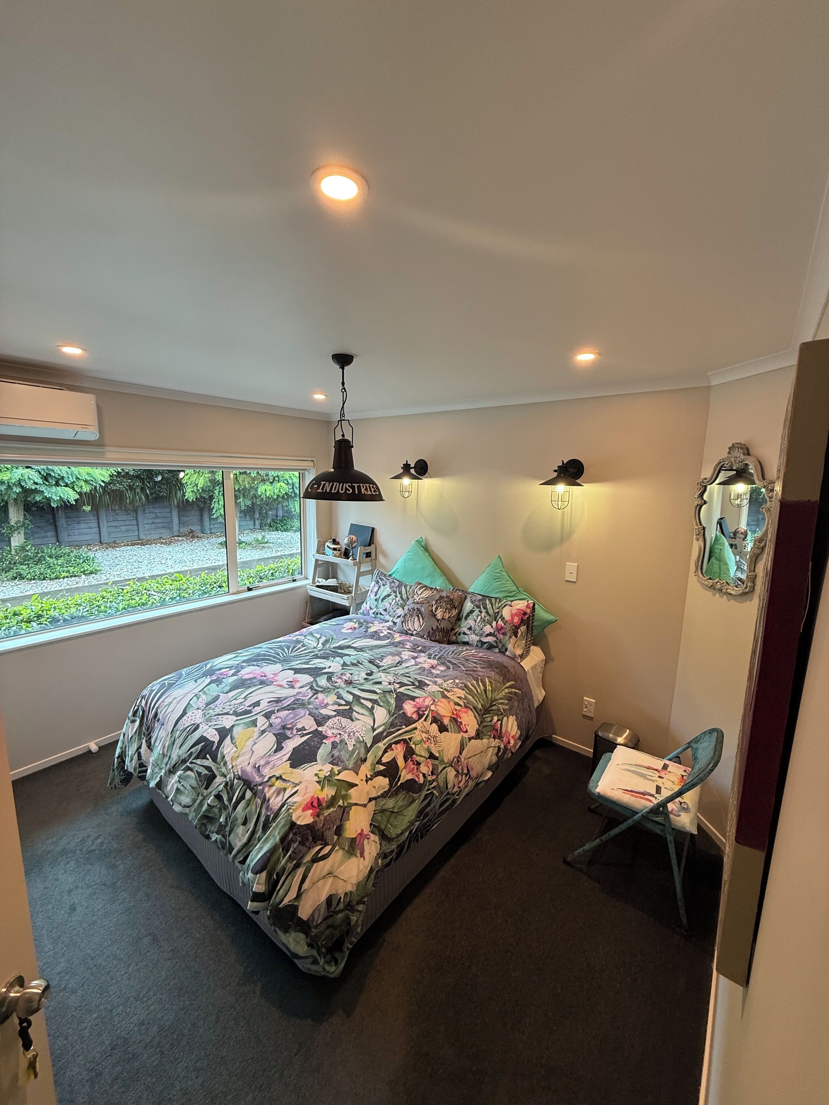 Un dormitorio con una cama grande, una ventana, una silla y un espejo.