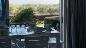 Une table à manger dressée avec des bols, des verres et des assiettes, donnant sur un jardin aménagé.