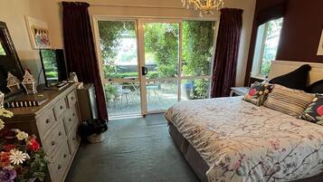 Een slaapkamer met een groot bed, een kaptafel, een kroonluchter en een schuifdeur naar een balkon.