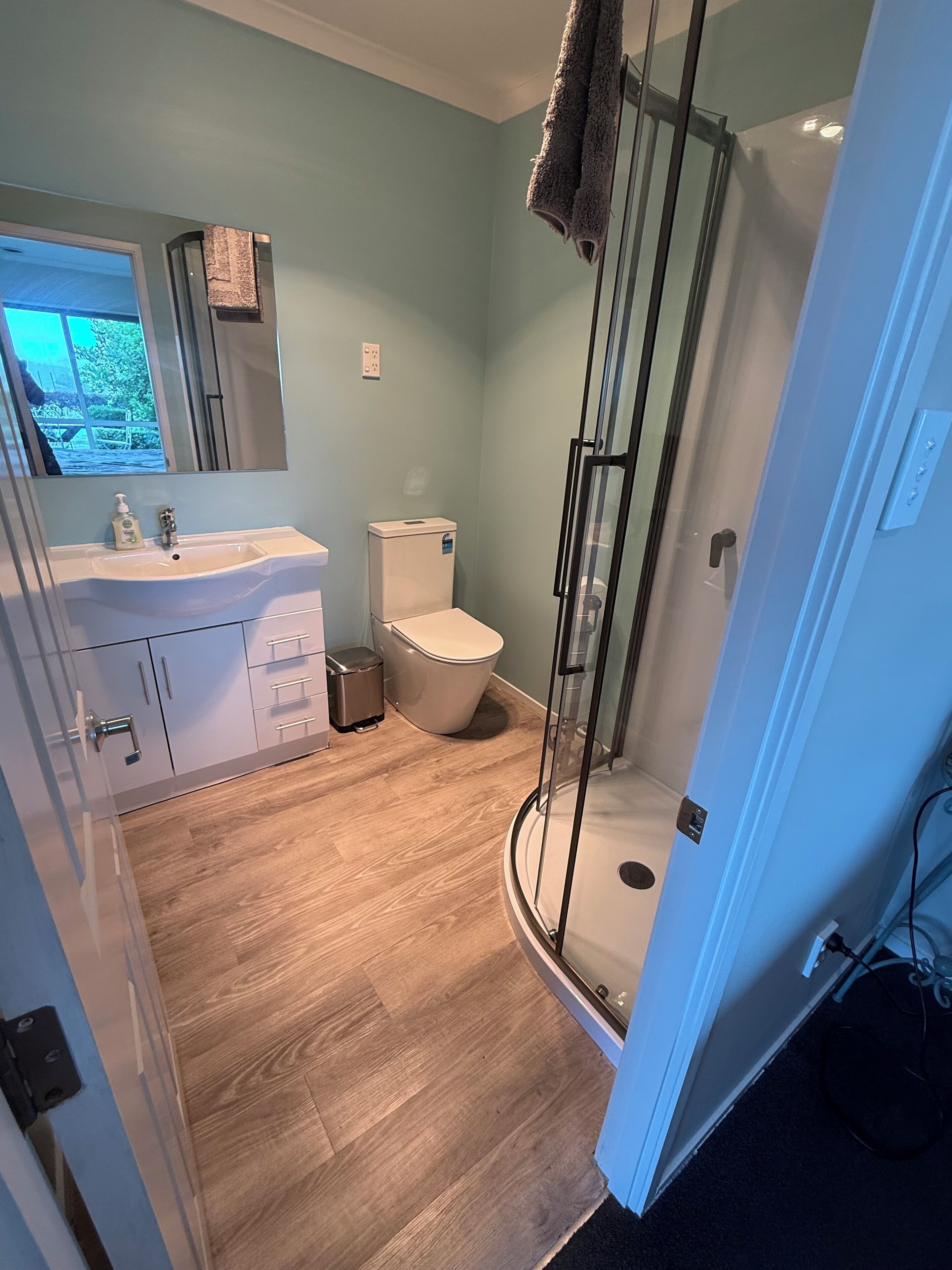 Un baño con inodoro, lavamanos y cabina de ducha de vidrio.