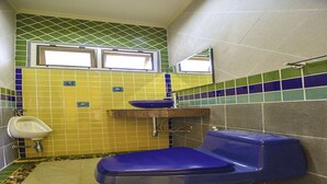 A bathroom with a blue toilet, a white urinal, and a sink with a blue basin. - Baan San Rak By Puppap (Cha-am)