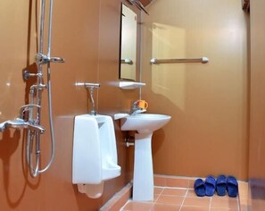 A bathroom with a shower, a sink, a toilet, and a pair of slippers on the floor. - Cat Ba Eco Lodge (Hai Phong)