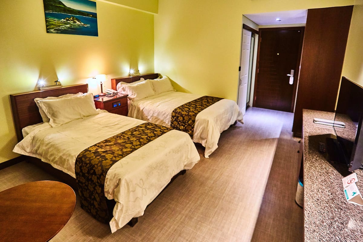 Une chambre d’hôtel avec deux lits, une petite table et un téléviseur.