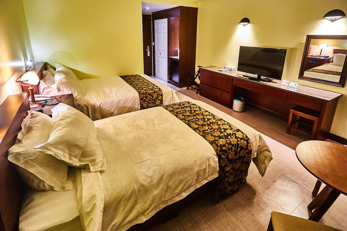 Une chambre d’hôtel avec deux lits, un bureau, une télévision et un miroir.