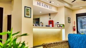 A reception area with a counter, a ceiling fan, and a framed picture on the wall. - Serenti Hotel (Saipan)