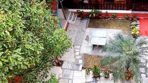 An outdoor patio area with a stone floor, surrounded by potted plants and a red railing. - Hotel Green Horizon (Kathmandu)