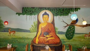 A mural of a seated Buddha figure with a serene expression, surrounded by a lush landscape with deer and peacocks. - Hotel Green Horizon (Kathmandu)