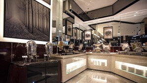 Een moderne hotellobby met een marmeren vloer, een gebogen receptiebalie en een groot schilderij van een bos aan de muur.