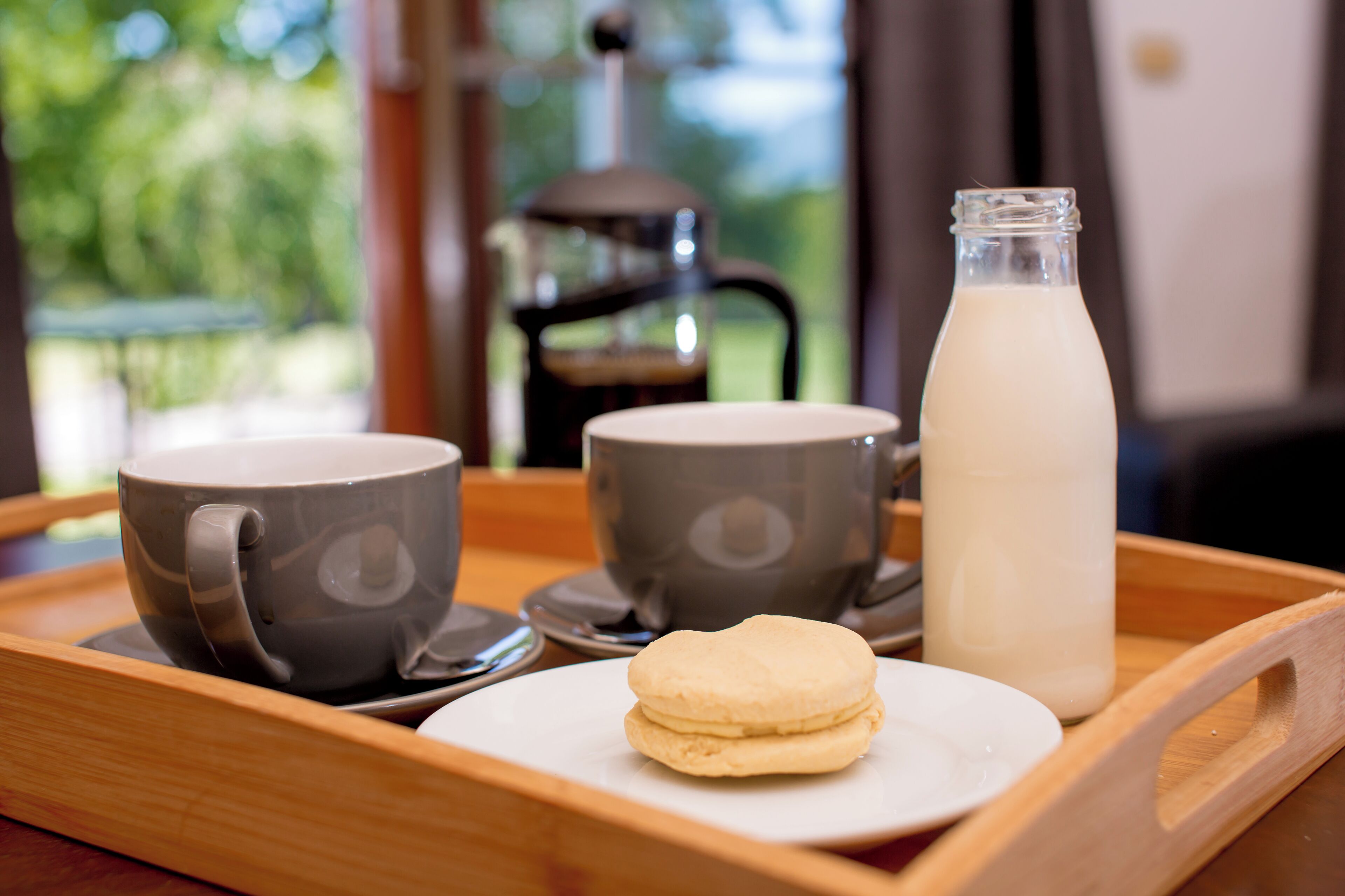A tray with two gray cups, a glass bottle of milk, and a plate with two cookies.