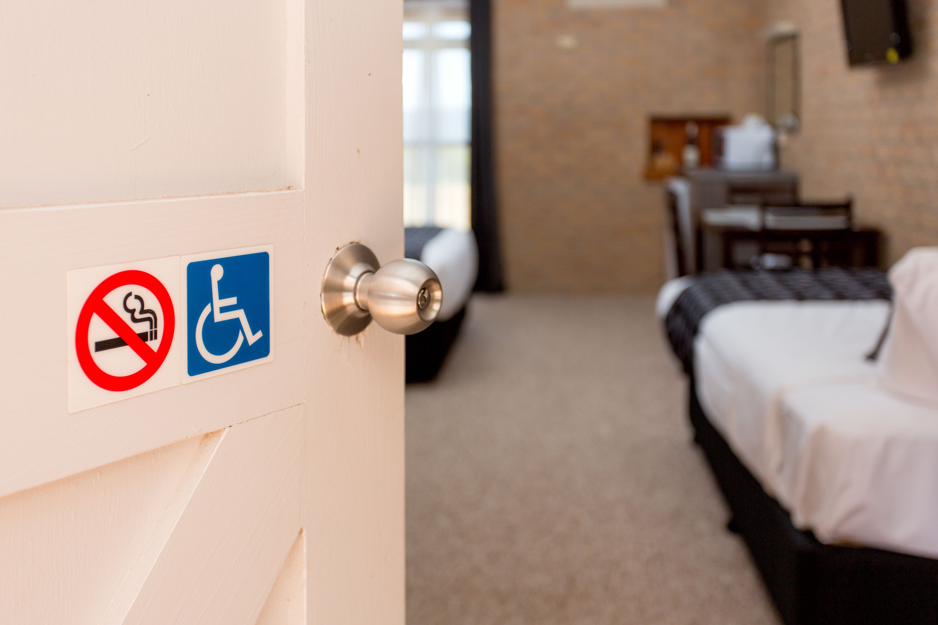 A hotel room with a bed, a desk, and a chair. There are no visible windows or views.