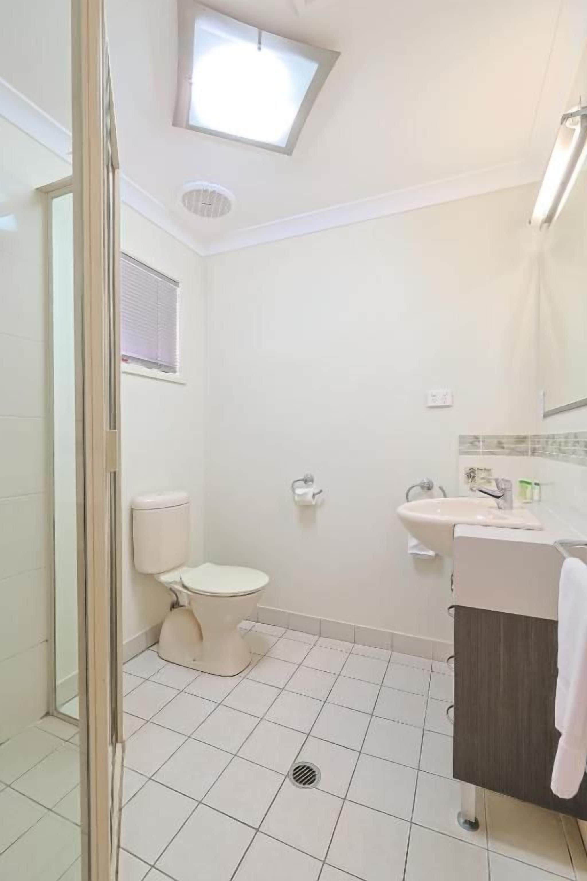 Un baño con inodoro, lavamanos y zona de ducha.