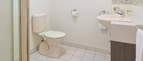 Un baño con inodoro, lavamanos y zona de ducha.