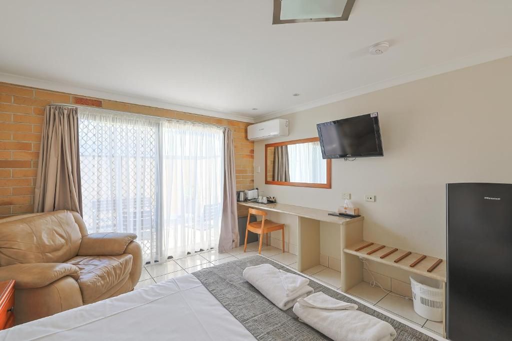 Une chambre d’hôtel comprenant un lit, un bureau, une télévision et un coin salon.