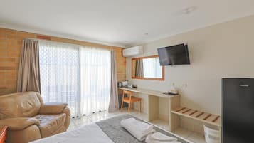 A hotel room with a bed, a desk, a television, and a seating area.